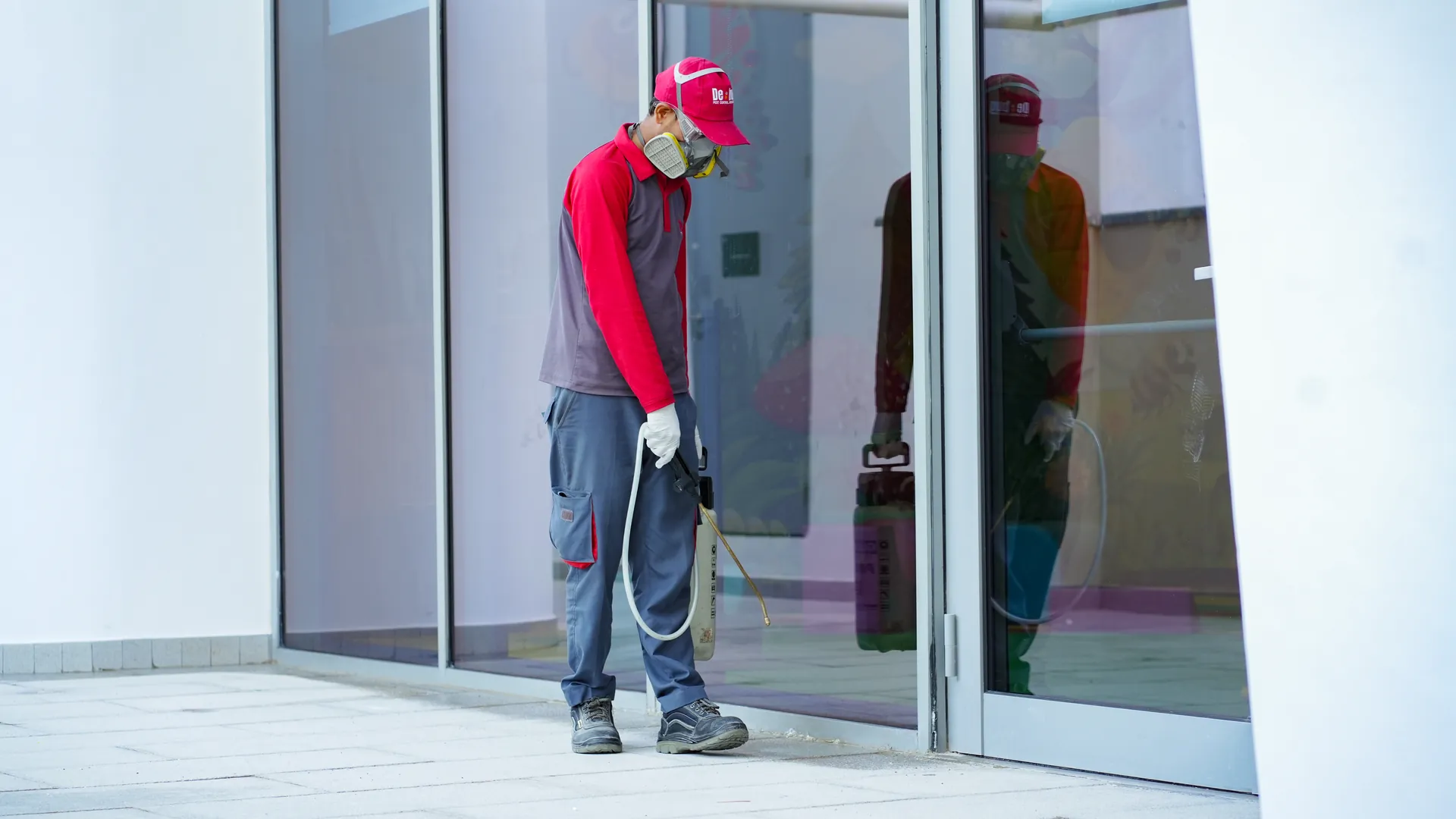 Pest control technician spraying a commercial entrance